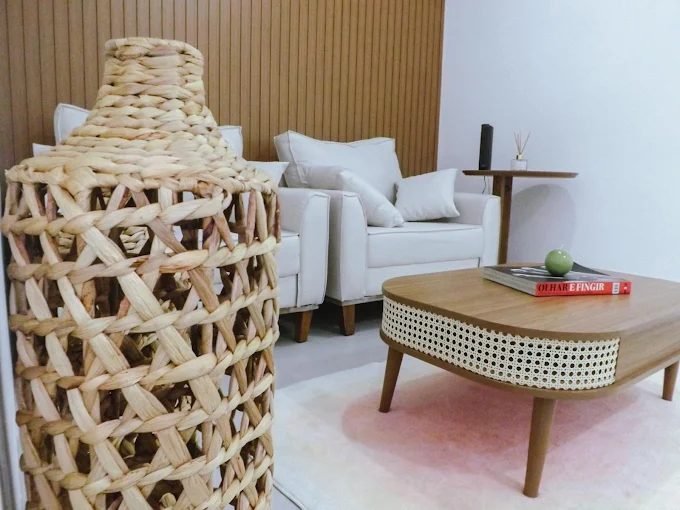 Recepção do consultório, com poltrona clara, mesa de centro de madeira e luminária de fibra natural